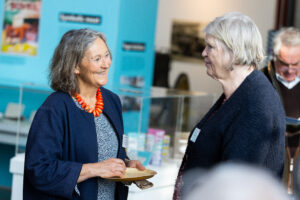 Two smiling women having a conversation, whilst one holds a canape.