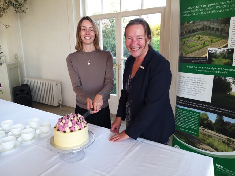 Karina Flynn and Jenifer White MBE, cutting a cake at a 'Suffolk's Unforgettable Garden Story' event